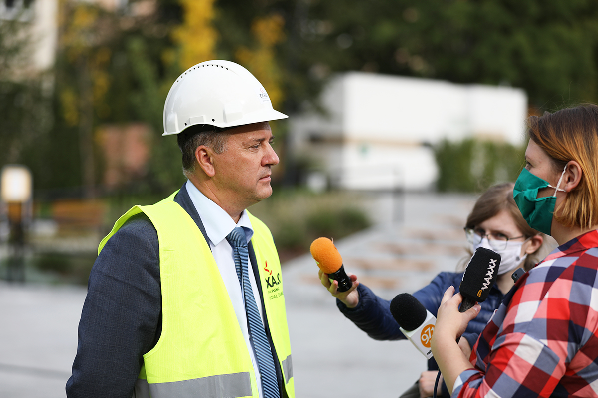 Pracownik urzędu ubrany w odblaskową narzutę i kask udziela wywiadu dla radio RMF MAXX.