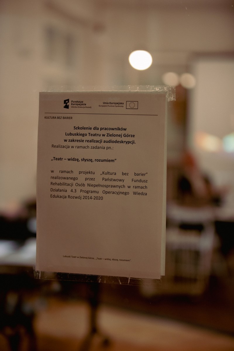 Informacja zawieszona na szkle odnośnie szkolenia z audiodeskrypcji. 